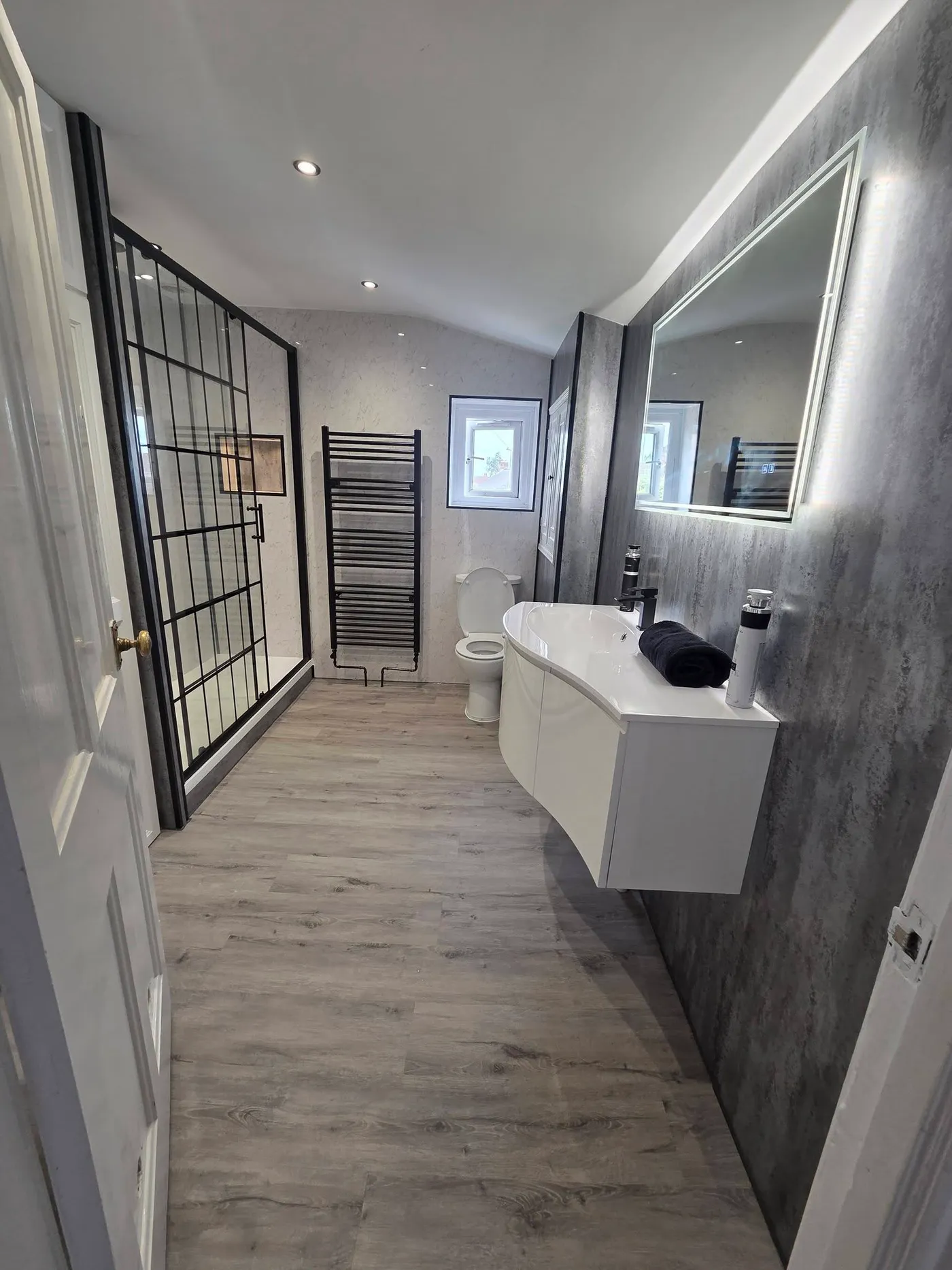 The finished bathroom viewed from the doorway, with a grid shower enclosure and floating vanity.