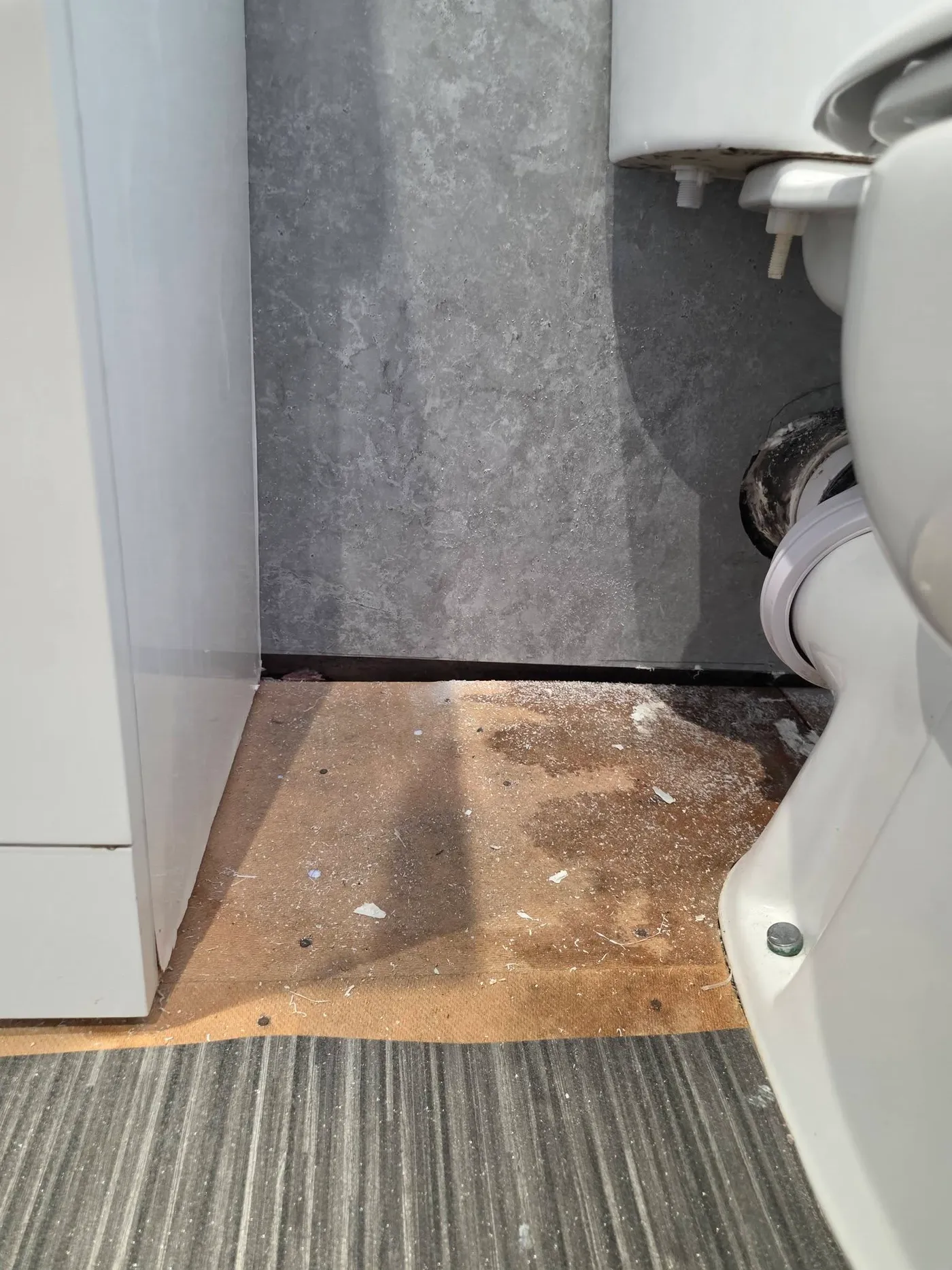 An unfinished floor area beside the toilet and shower.