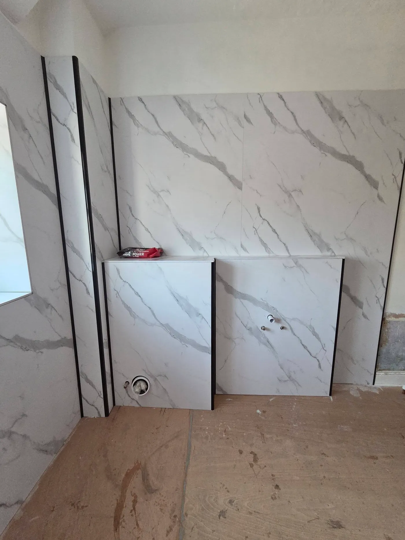 Marble-effect wall panels and black trims fitted around the boxing-in.
