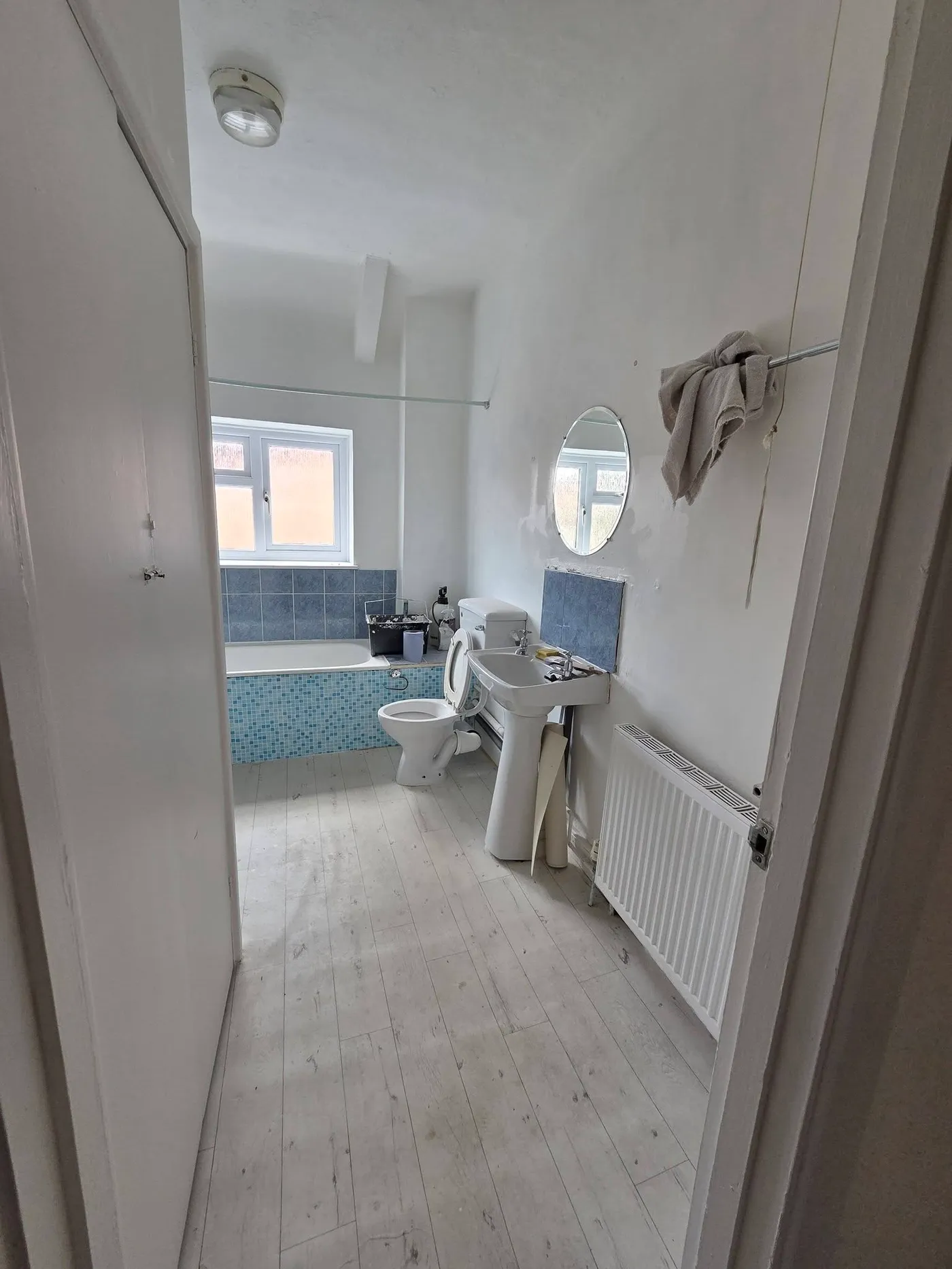 The original bathroom viewed from the doorway, with blue tiles and older fittings.
