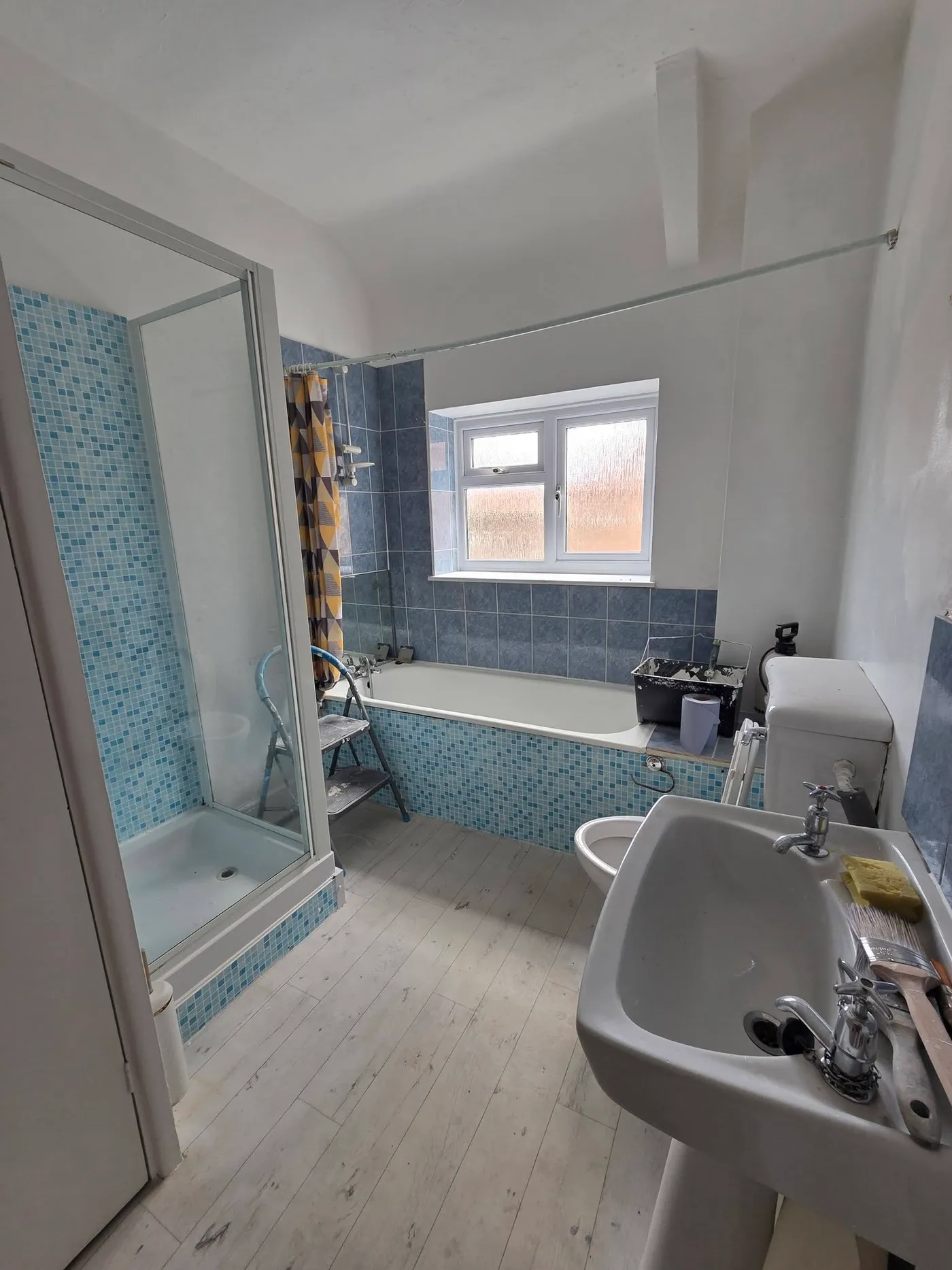 A closer view of the original blue-tiled shower and bathroom fittings.