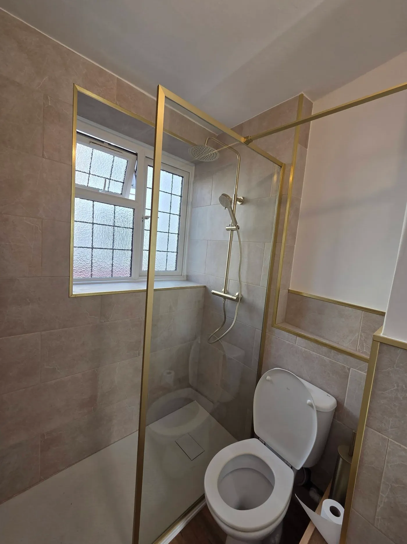 The completed bathroom with a glazed shower enclosure and tiled walls.